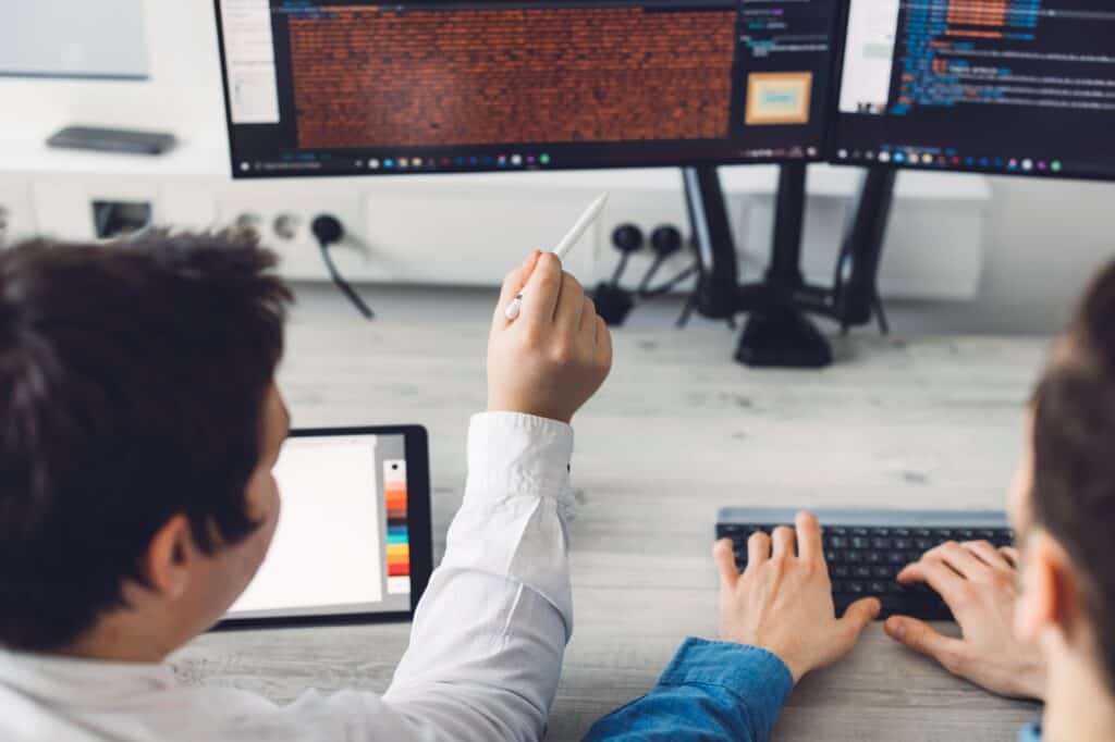 Over the shoulder close up view two programmers working on wordpress database optimization